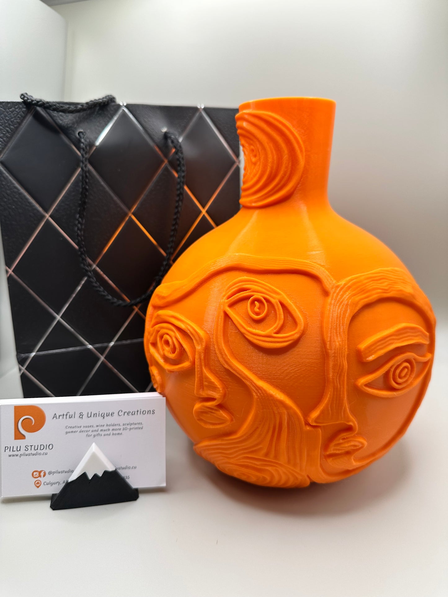 Close-up of artistic sculptural vase featuring multiple abstract faces in relief