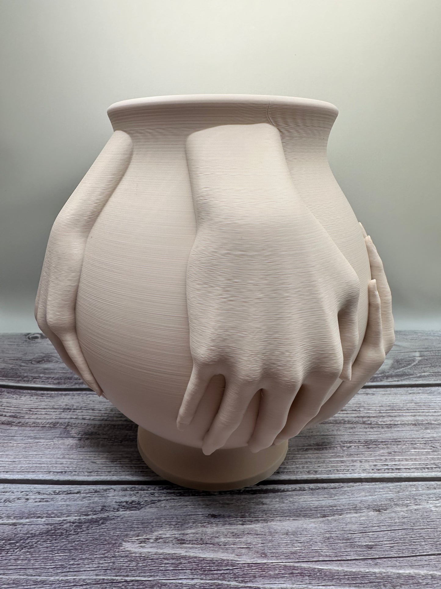 Large symbolic vase with hands holding it, artistic and emotional home accent