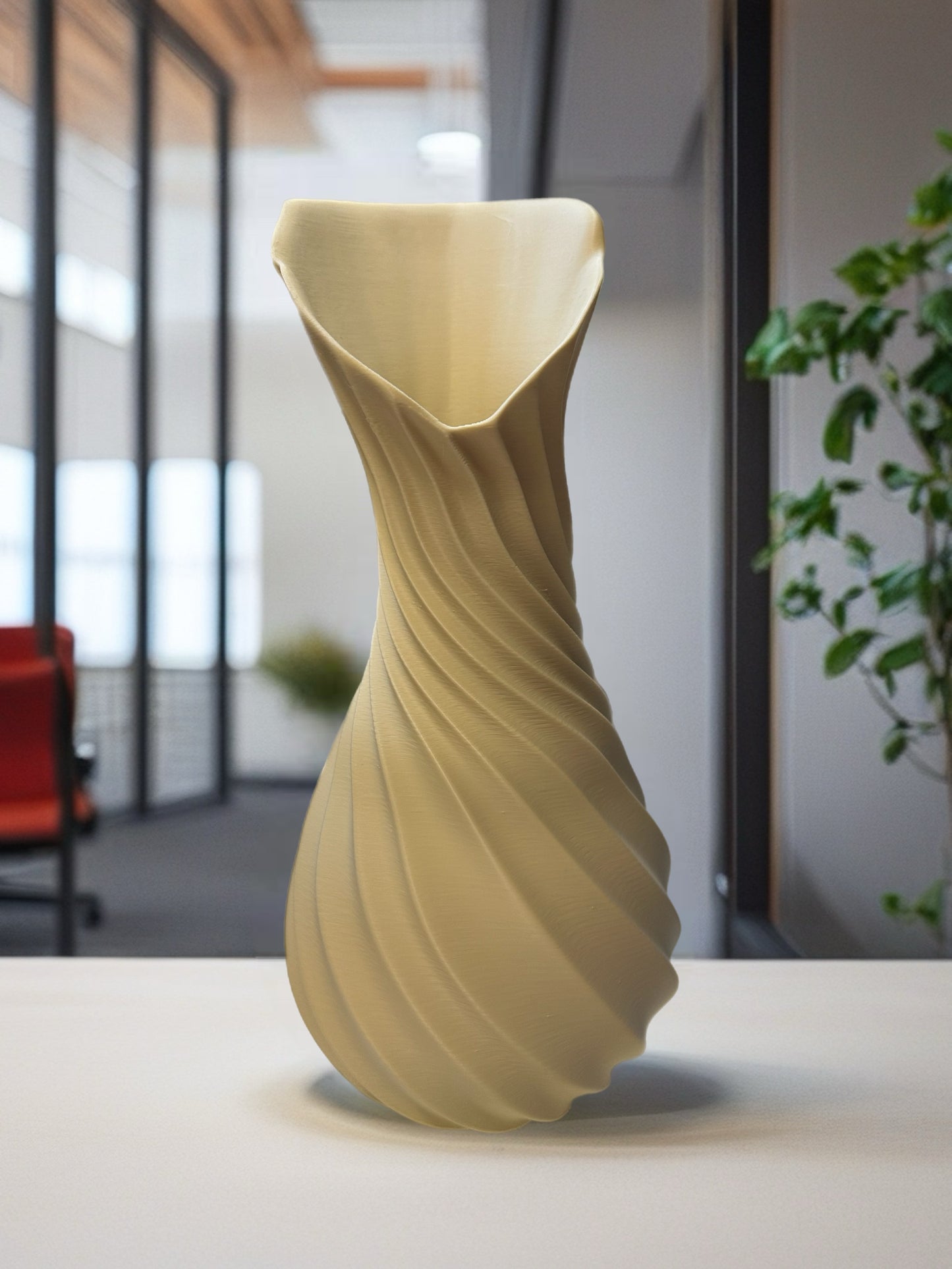 Elegant beige sculptural vase with spiral texture displayed on a white table in a modern office setting.