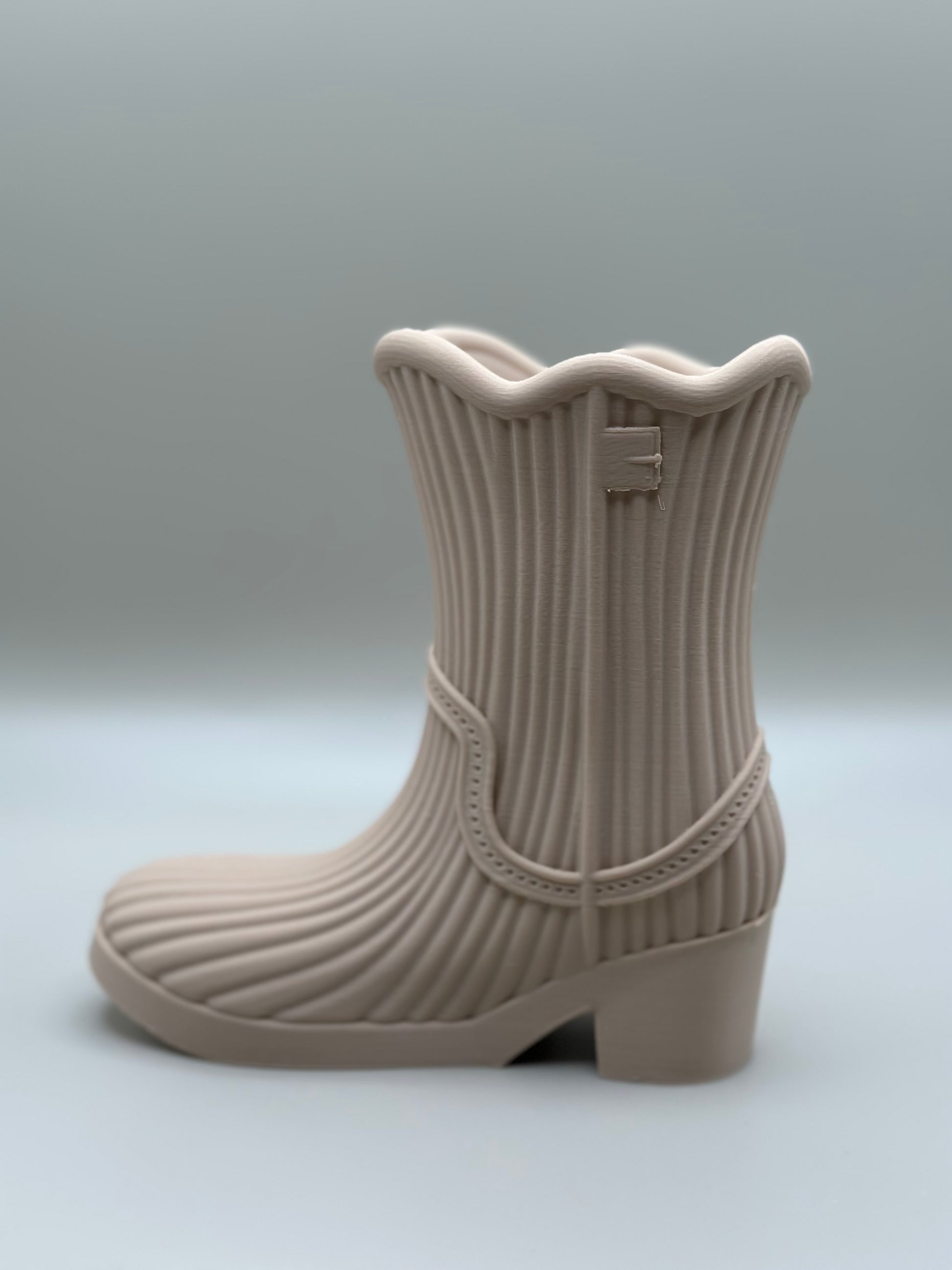 3D printed mini boot in beige used as a flower vase or pen holder