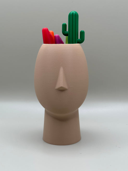 3D printed face-shaped desk organizer with pens and cactus accessory