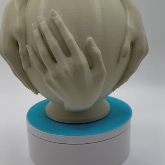 art piece with hands embracing a vase