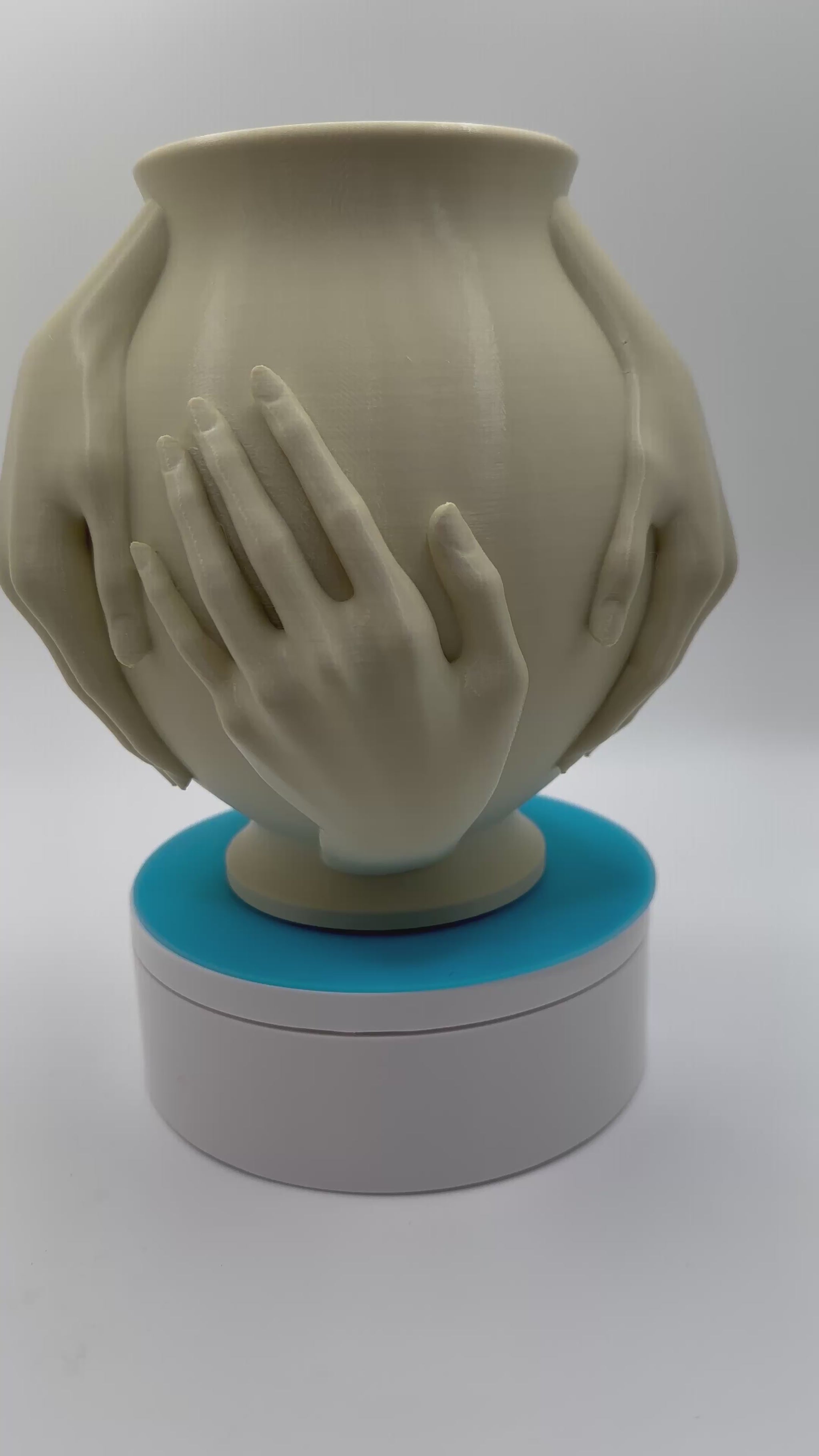 art piece with hands embracing a vase